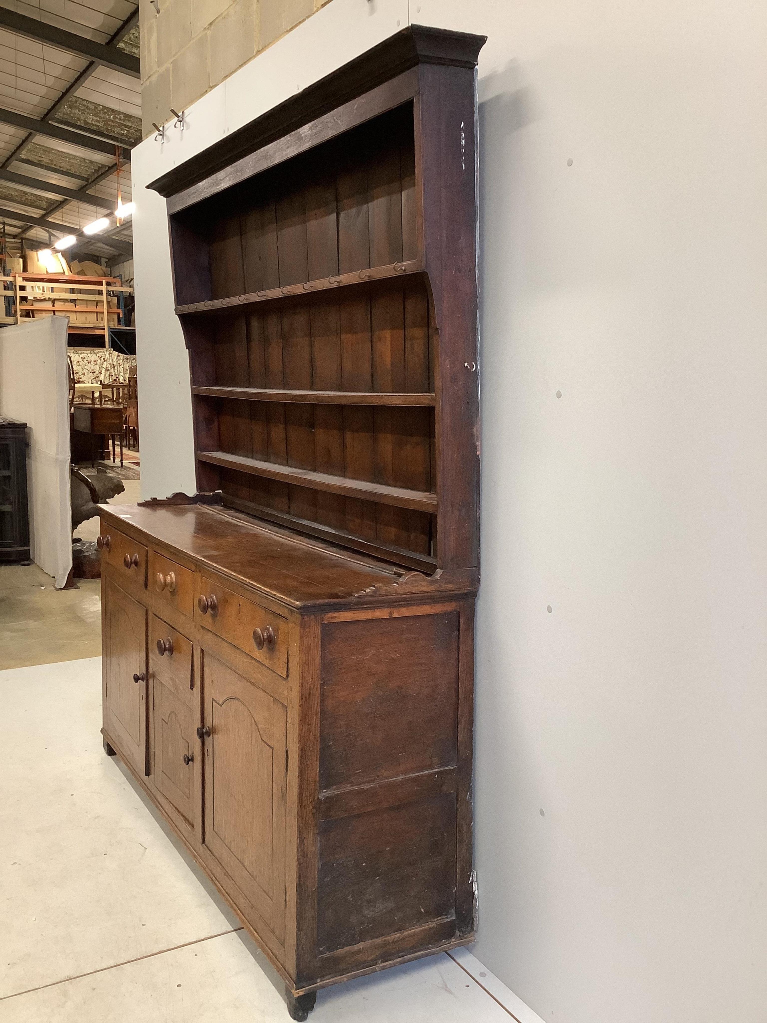 A George III oak dresser with boarded rack, width 168cm, depth 46cm, height 204cm. Condition - poor, lacks back legs